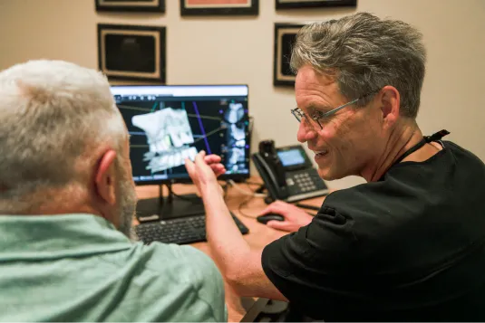 doctor showing patient monitor with model of teeth