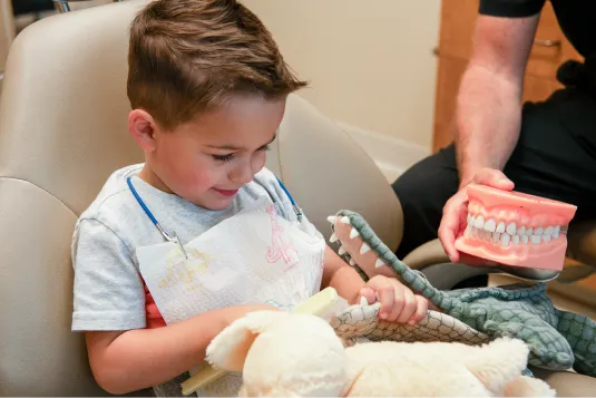 kid brushing aligators teeth