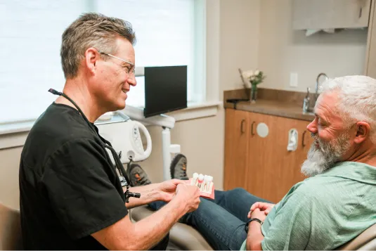 doctor showing patient model of teeth