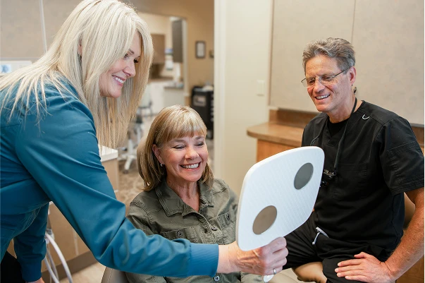 Dr. Johnson showing a patient their new teeth with a mirror